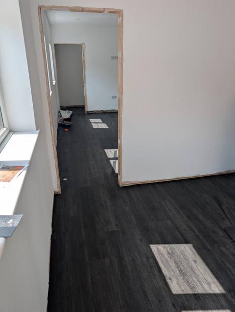 Open-plan room and doorway with dark plank floor