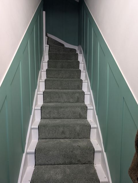 Carpet runner up the stairs between green panelling